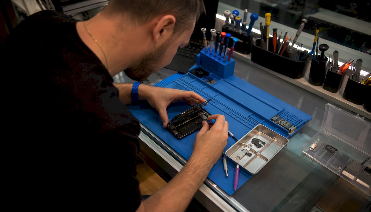 Technician replacing iPhone battery at workbench